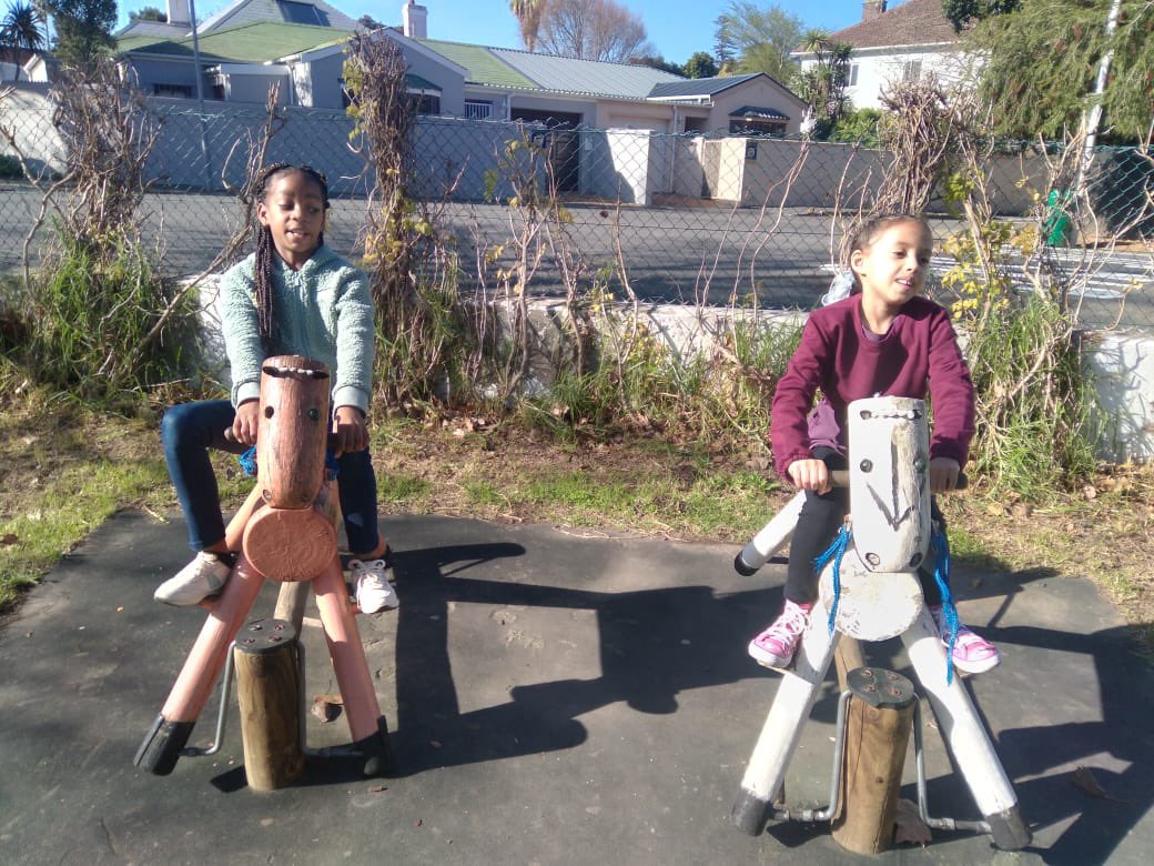 Kimberly and Phoenix on wooden horses in the park 