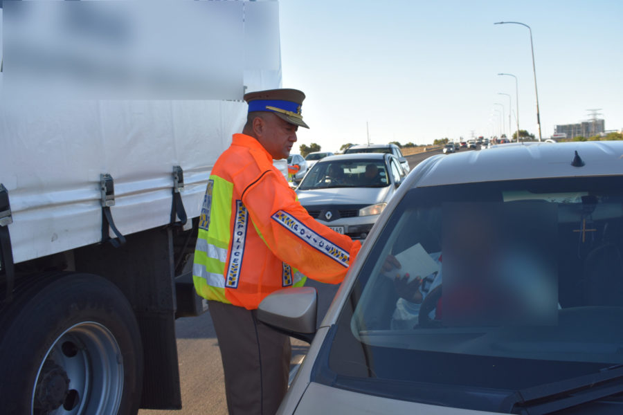 Metro police officer handing a pamphlet to a driver 