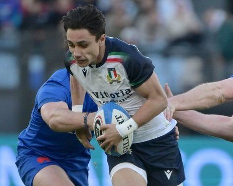 Italian fullback, Ange Capuozzo, bursting through two French defenders in their Six Nations encounter.