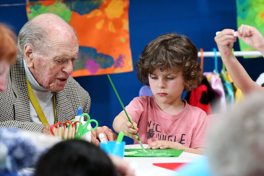 Elderly man paints with pre-schooler